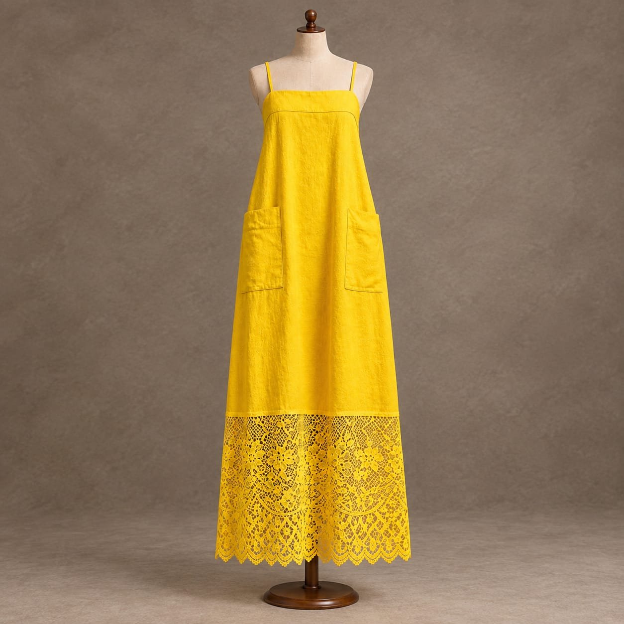 Women's bright yellow maxi dress with spaghetti straps, side pockets and floral lace hem displayed on a mannequin